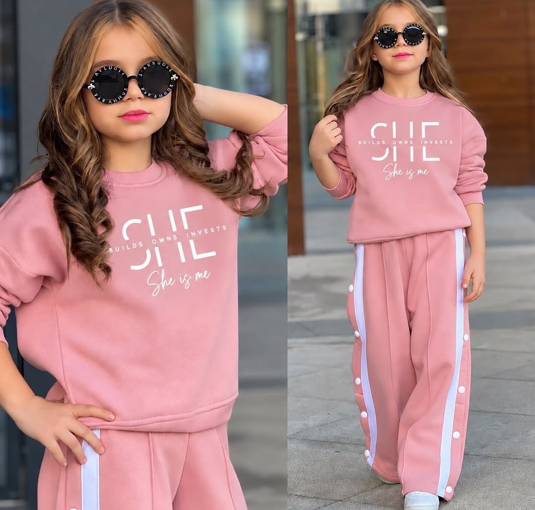 A child models a lavender sweatshirt and matching wide-leg track pants with white side stripes, shown in two full-length views under daylight.