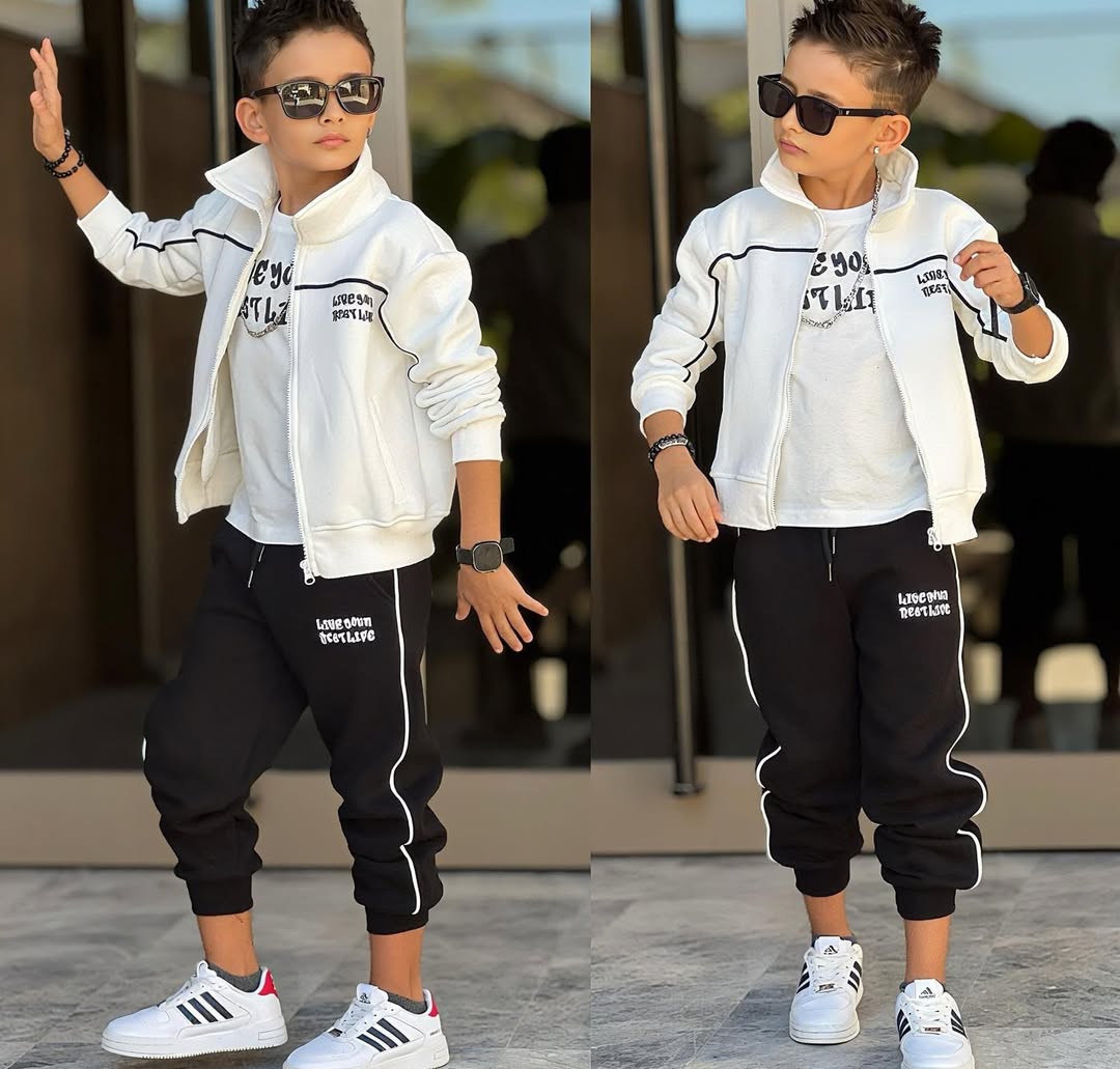 Two full-body views of a child wearing a white jacket with black pants, white sneakers and sunglasses, posed in front of glass doors in bright daylight.