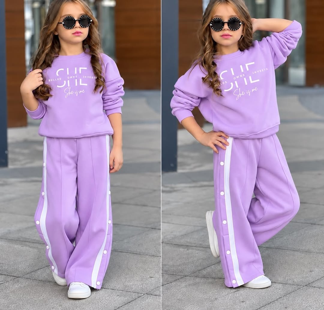 A child models a dark brown sweatshirt and matching wide-leg track pants with white side stripes outdoors, shown in two full-length views under daylight.